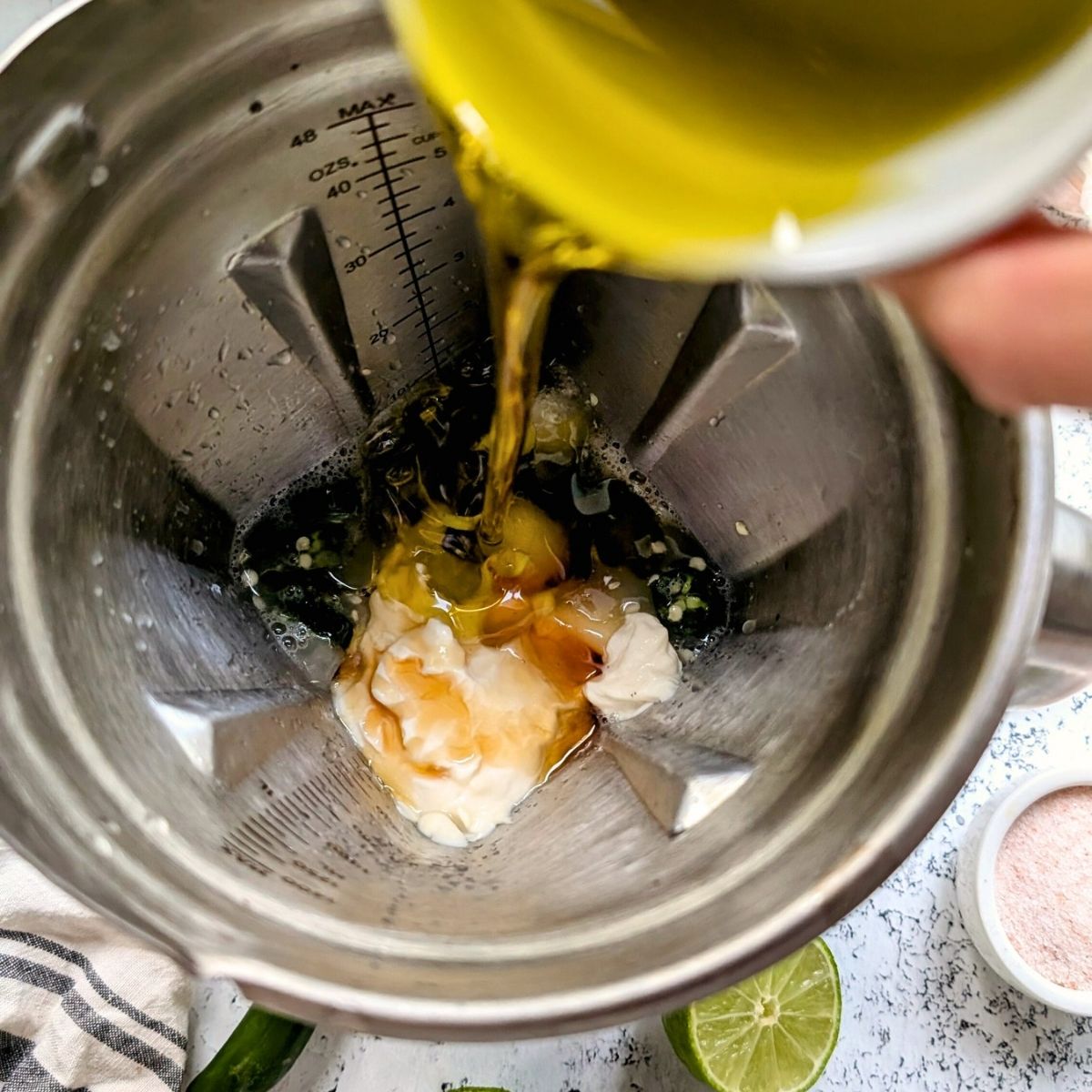 a blender with ingredients for jalapeno dressing being poured in and ready to be blended.