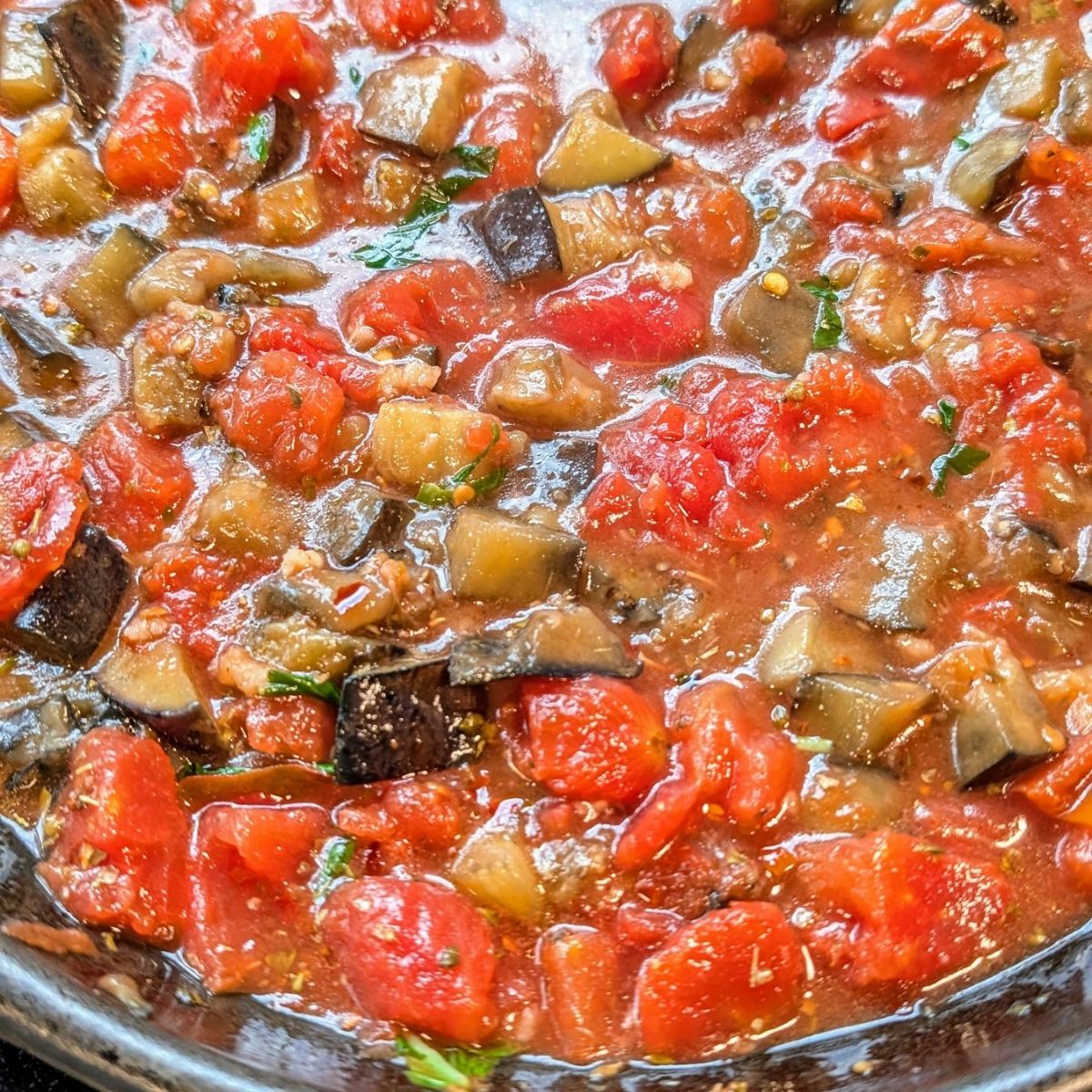 sicilian pasta sauce with eggplant and tomatoes with basil and spices simmering in a pot.