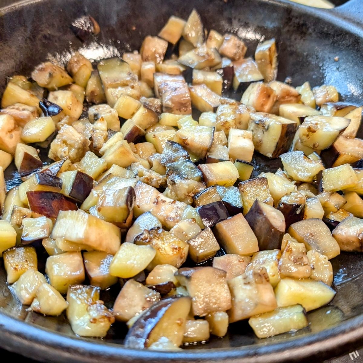 eggplant cooked in a cast iron skillet with salt and olive oil until it's glistening and golden.