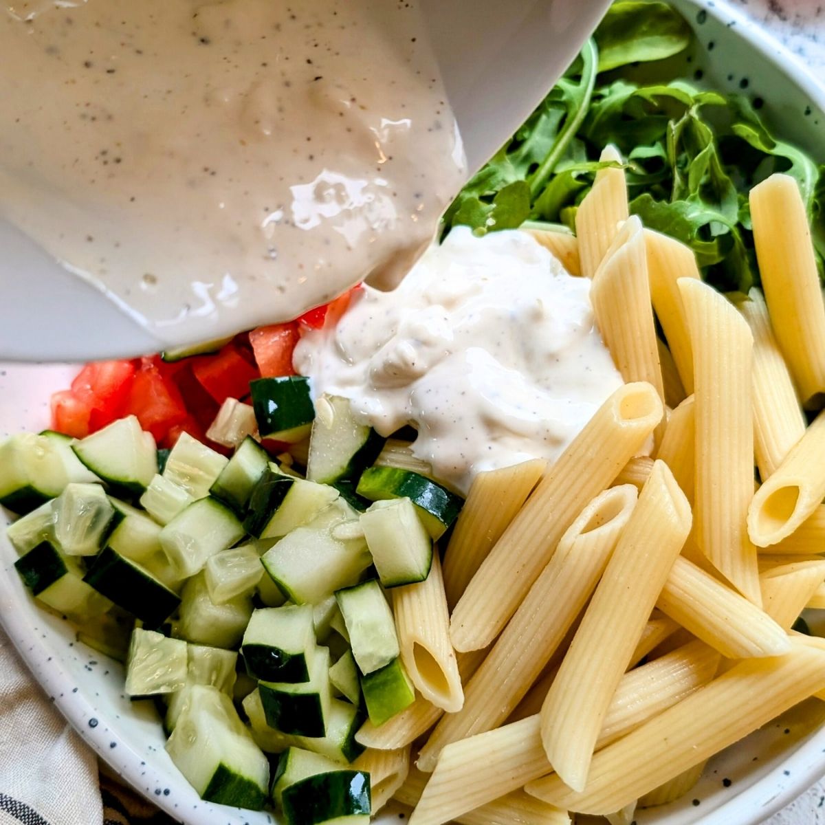 a big bowl of pasta salad with a creamy mayonnaise dressing poured over the top.