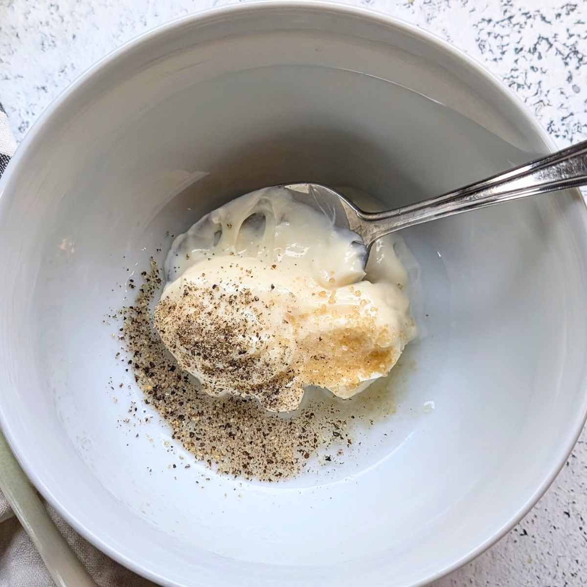 a bowl full of salad dressing ingredients like mayo, white vinegar, sugar, and salt, and pepper.