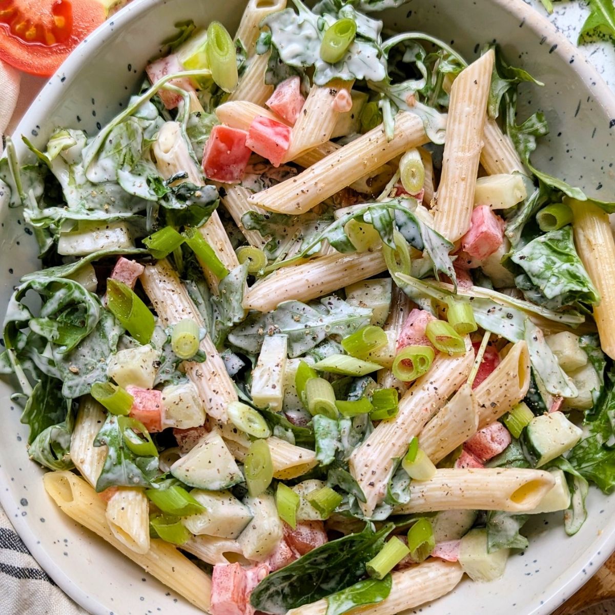 creamy arugula pasta salad recipe with penne noodles cucumbers tomato and a creamy mayo dressing.