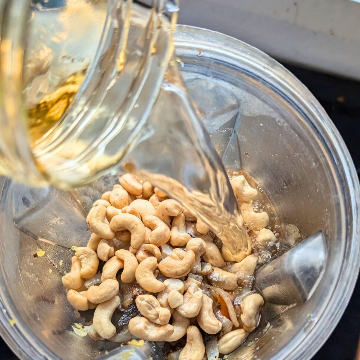 a blender of acorn squash cashews and vegetable stock making pasta sauce vegan and gluten free.