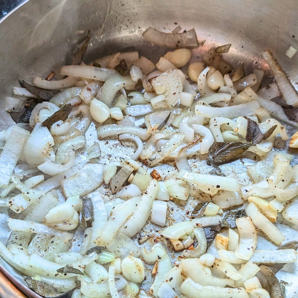 browning onions and garlic with sage in a pan to make acorn squash sauce.