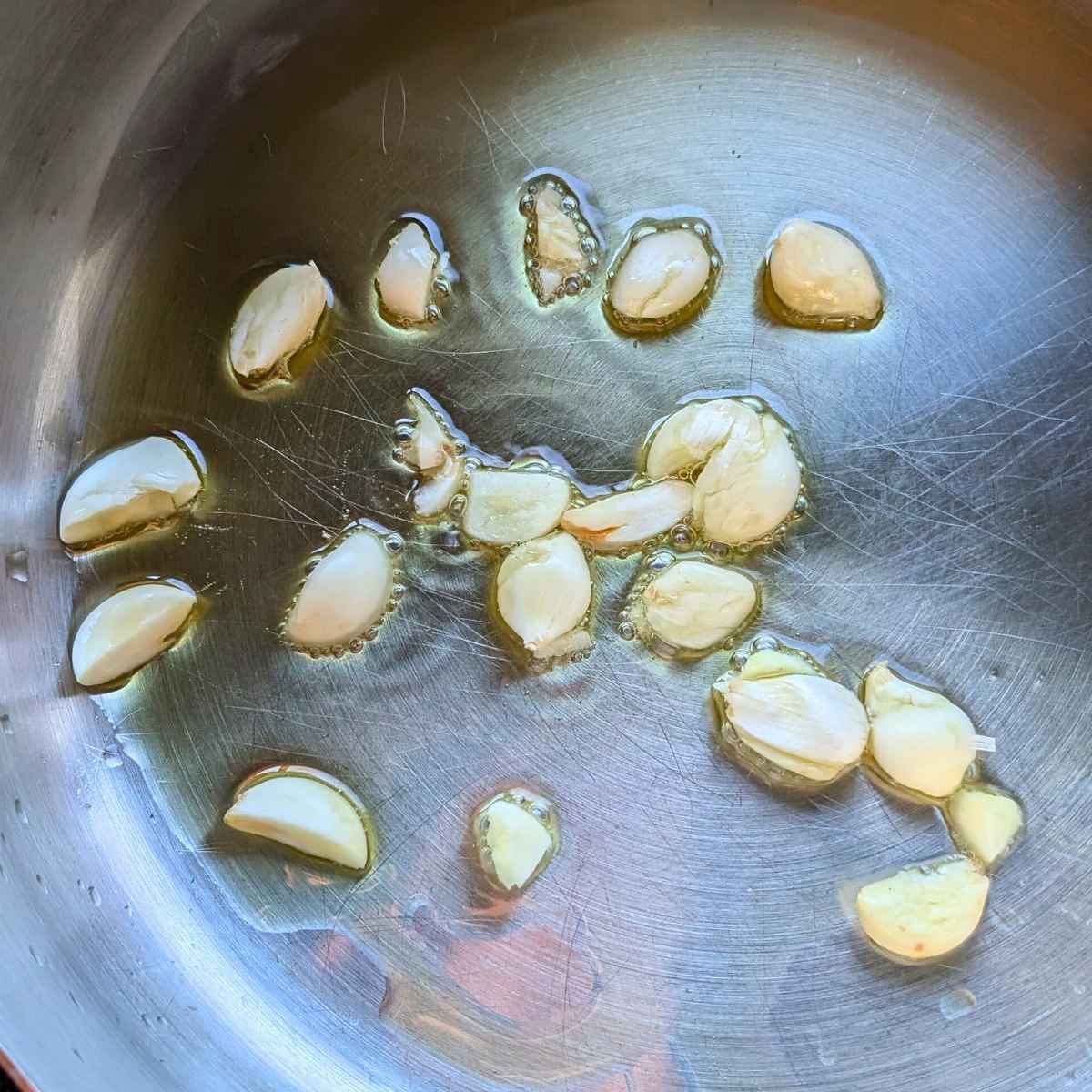 olive oil and garlic sautéing in a pan to make acorn squash pasta sauce.