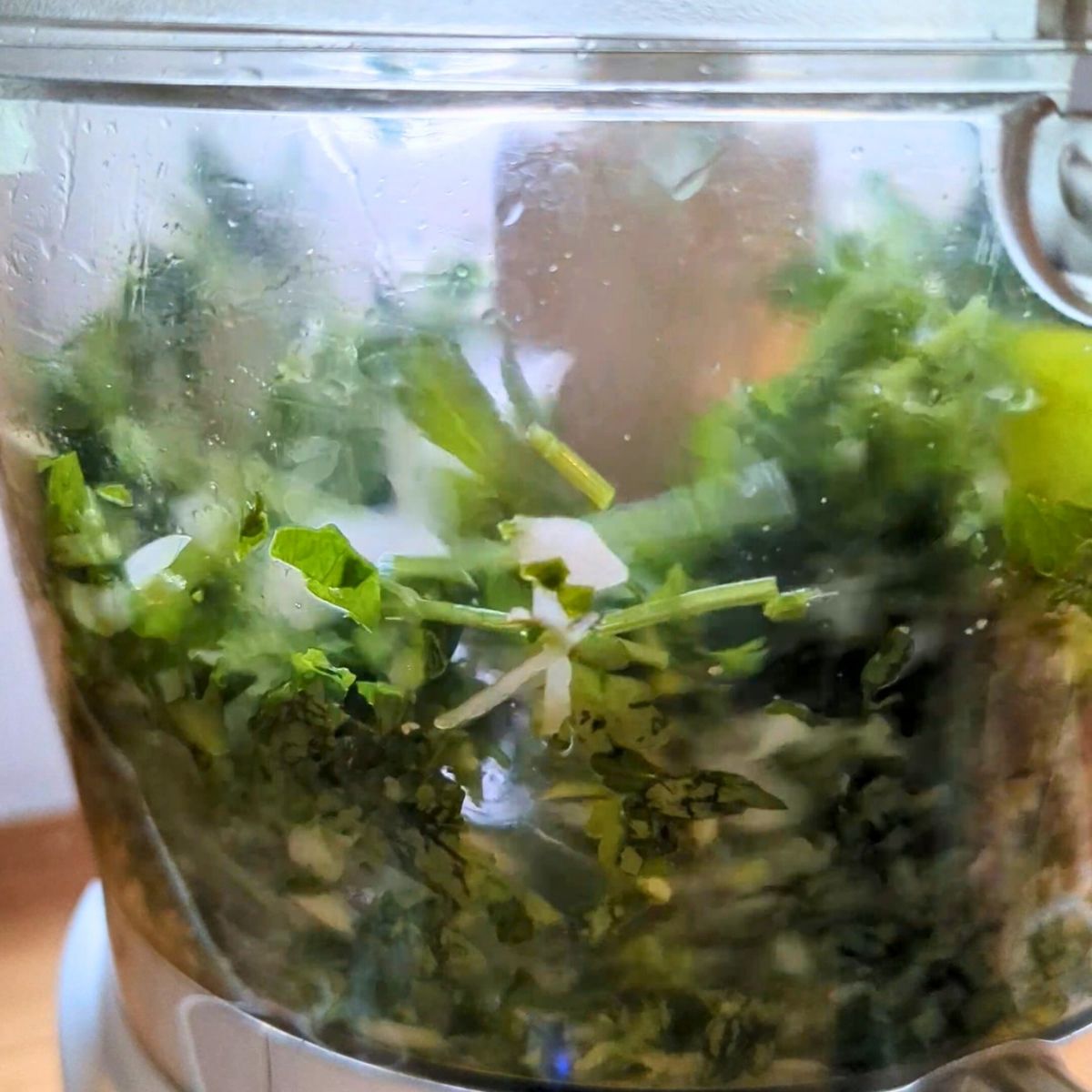 a food processor full of onion and parsley for making greek meatballs