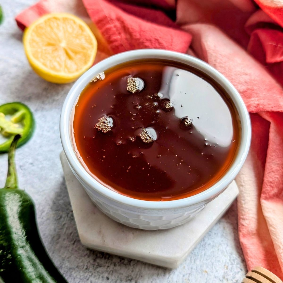 smoked hot honey recipe with paprika and jalapeno peppers strained out and placed into a ramekin.