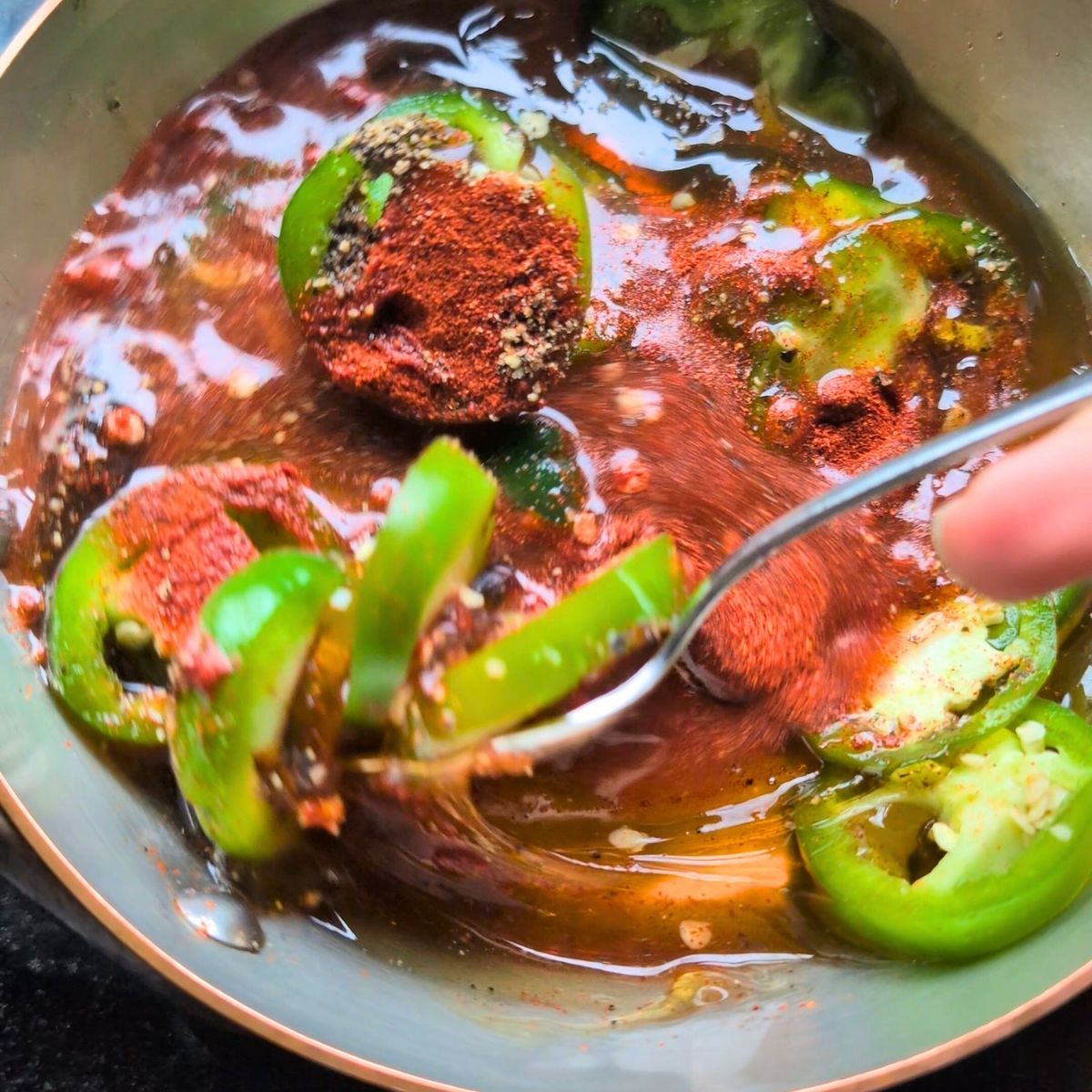 honey with sliced jalapeno peppers, paprika, and lemon juice, and black pepper stirred in a saucepan.