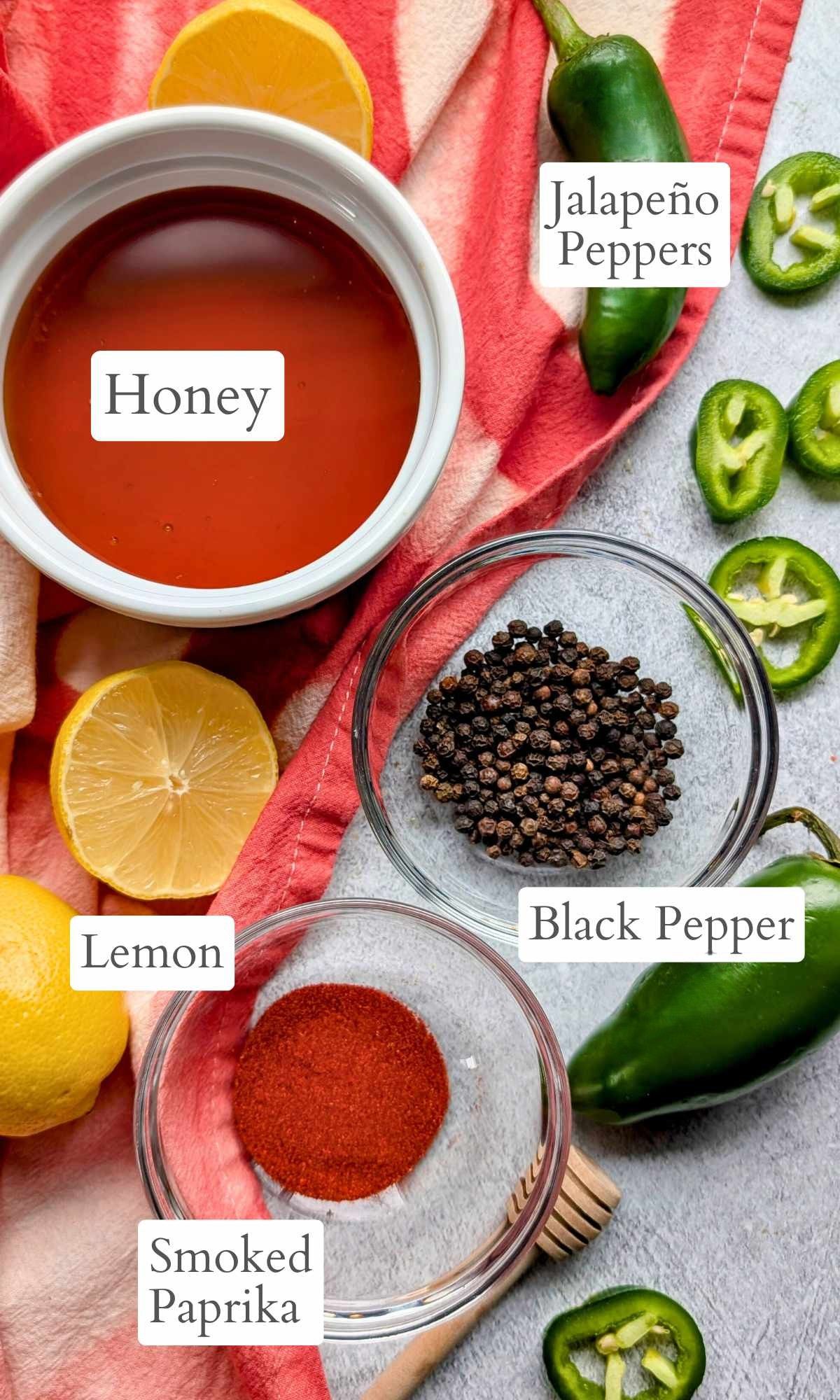 ingredients for hot honey like jalapeno peppers, lemon, smoked paprika, and black pepper.