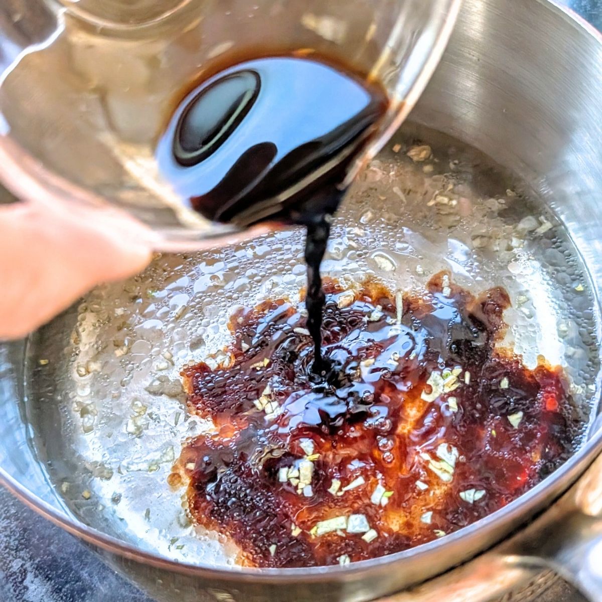 vegetable stock and soy sauce being pored into a boiling pot to make vegan udon noodle soup