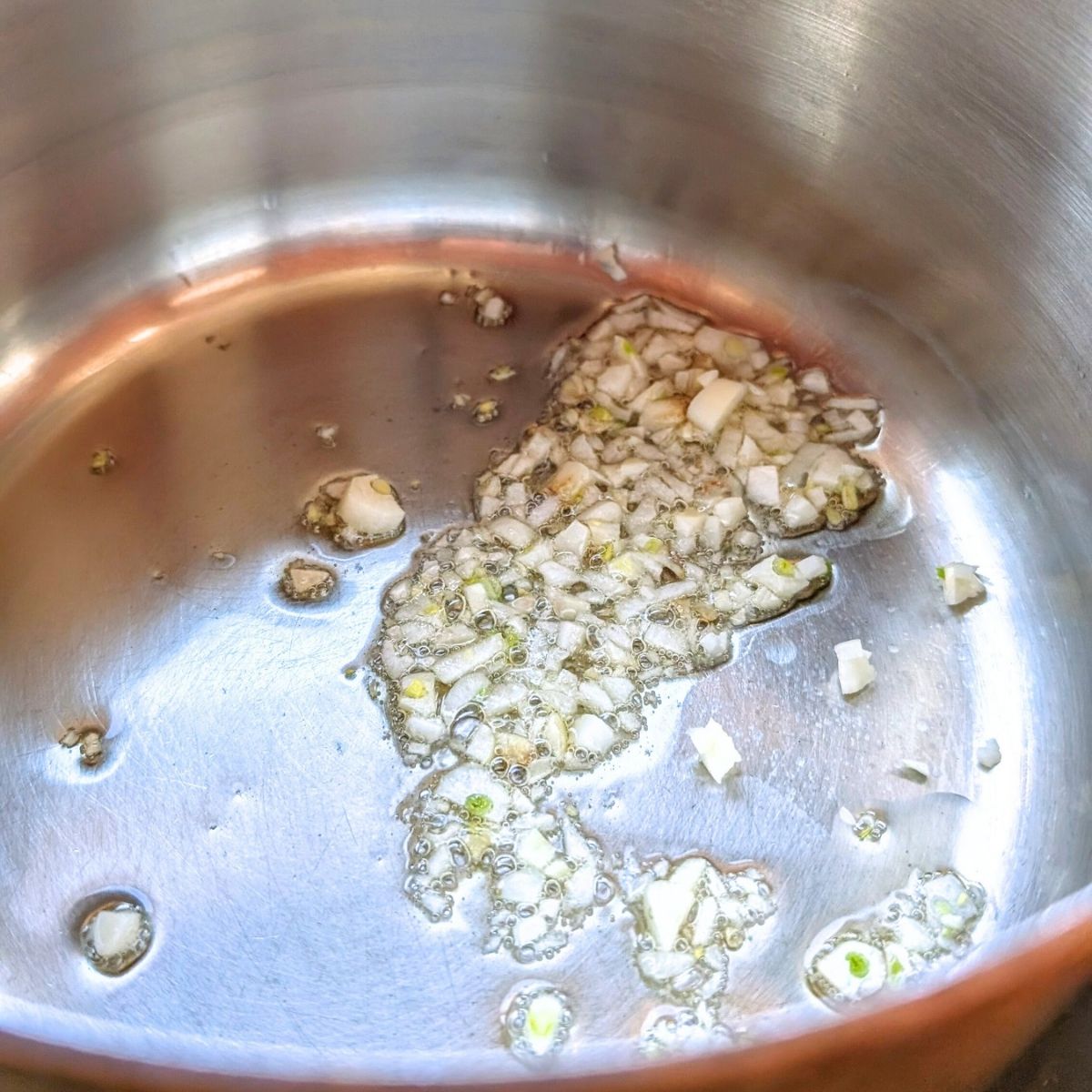 a pot with sesame oil and garlic to make vegetarian udon soup