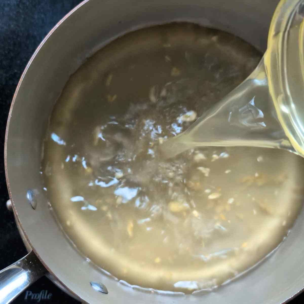 vegetable stock poured into a pot with garlic and toasted sesame oil to make egg drop soup