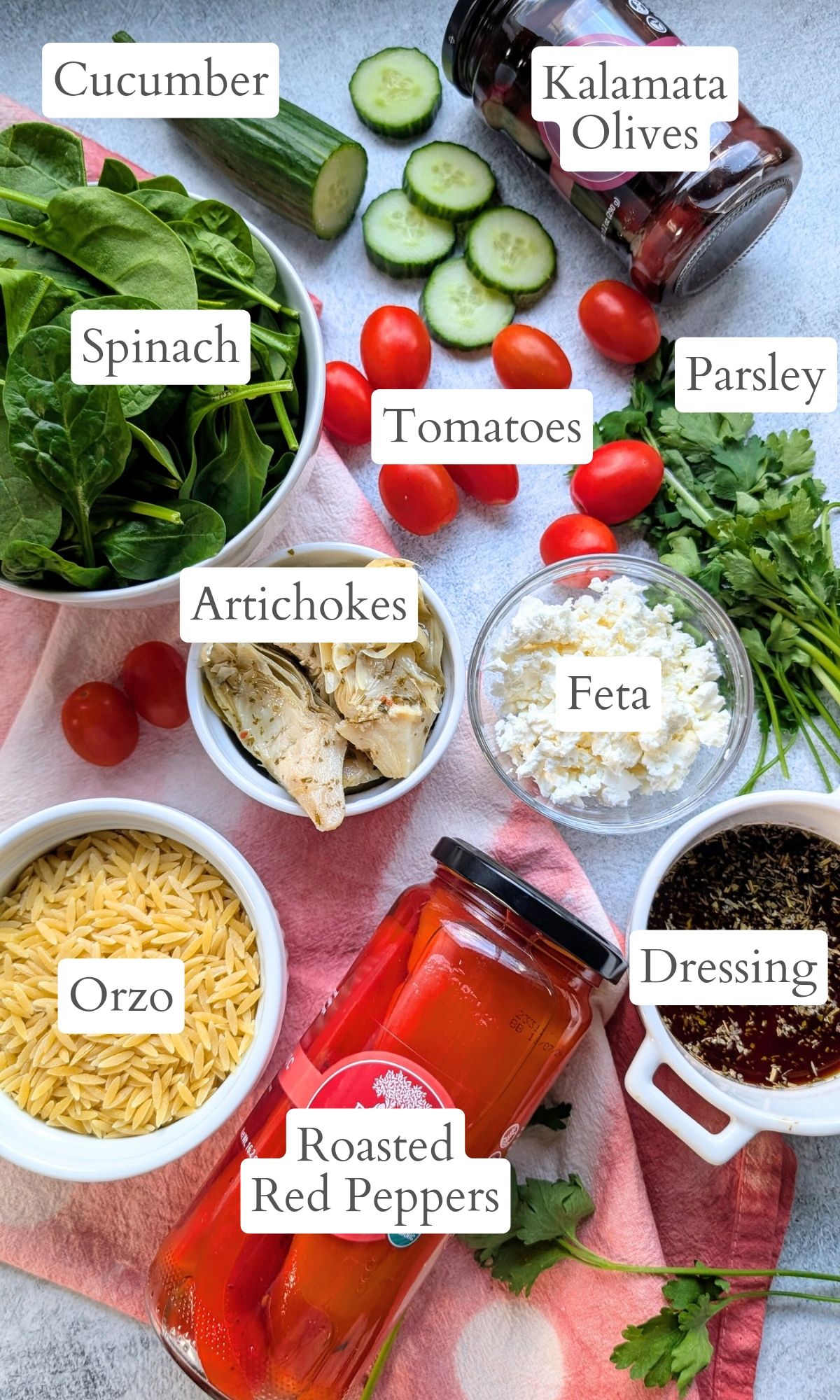 ingredients for artichoke pasta salad with vegetables and orzo pasta and feta cheese and fresh herbs.