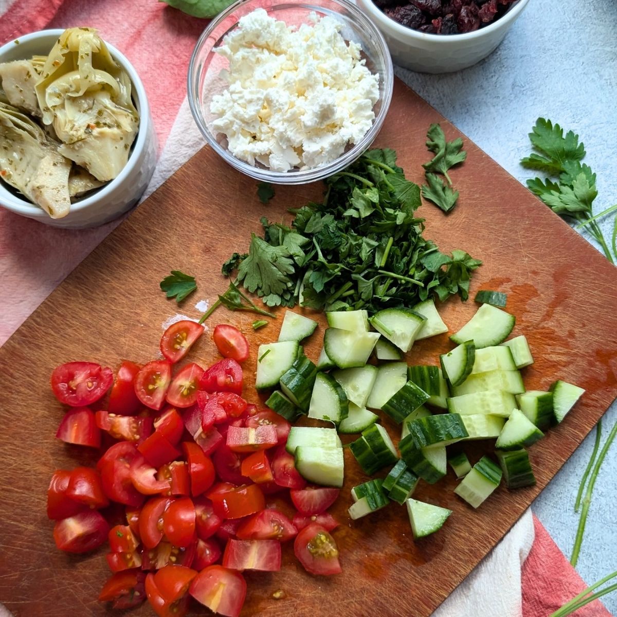 chopped vegetables for pasta salad: artichokes, tomatoes, cucumbers, and fresh parsley with feta cheese.