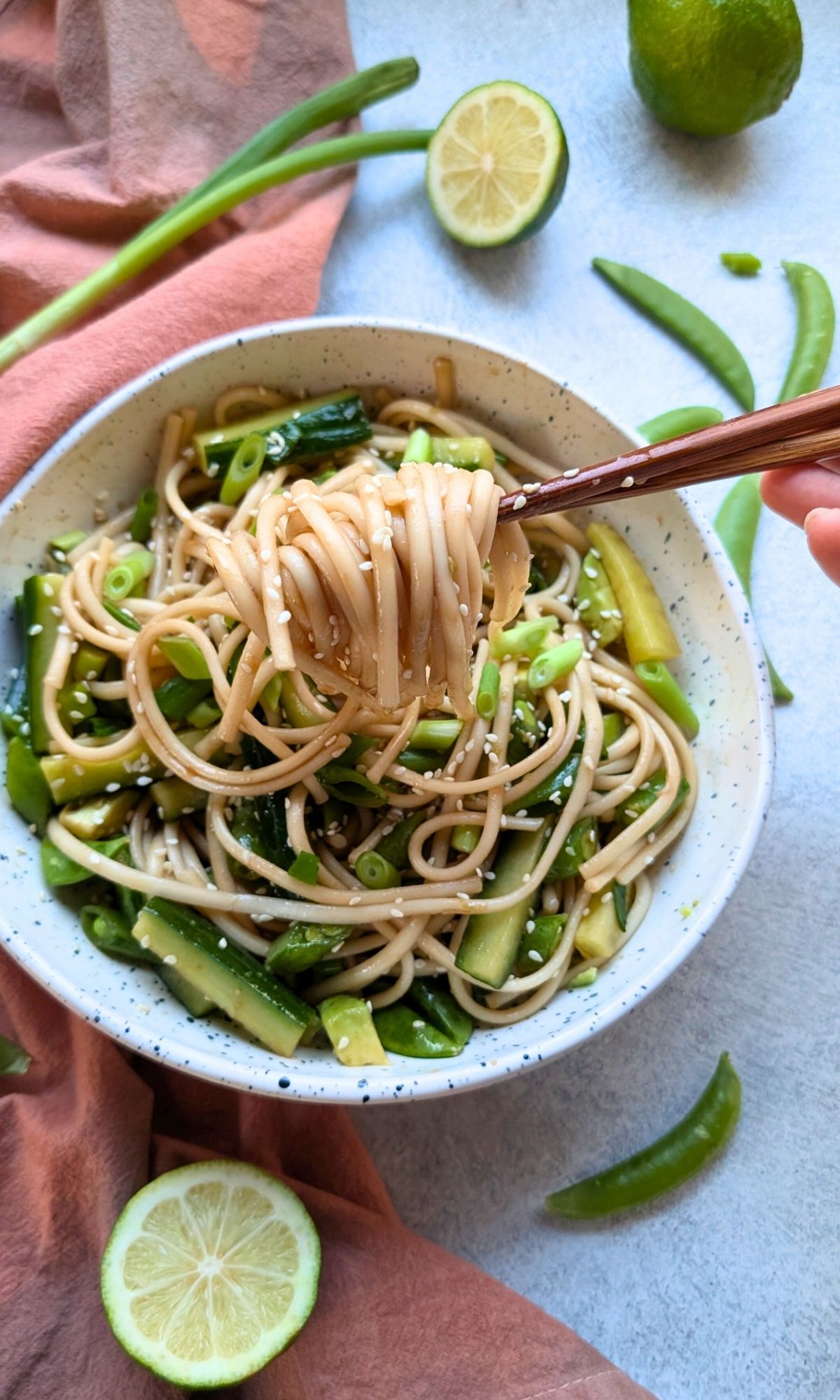 udon noodle salad with chopsticks being eaten with sesame seeds and green vegetables.