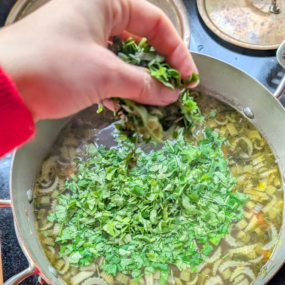 a pot of soup with fresh parsley leaves added for flavor and herby taste