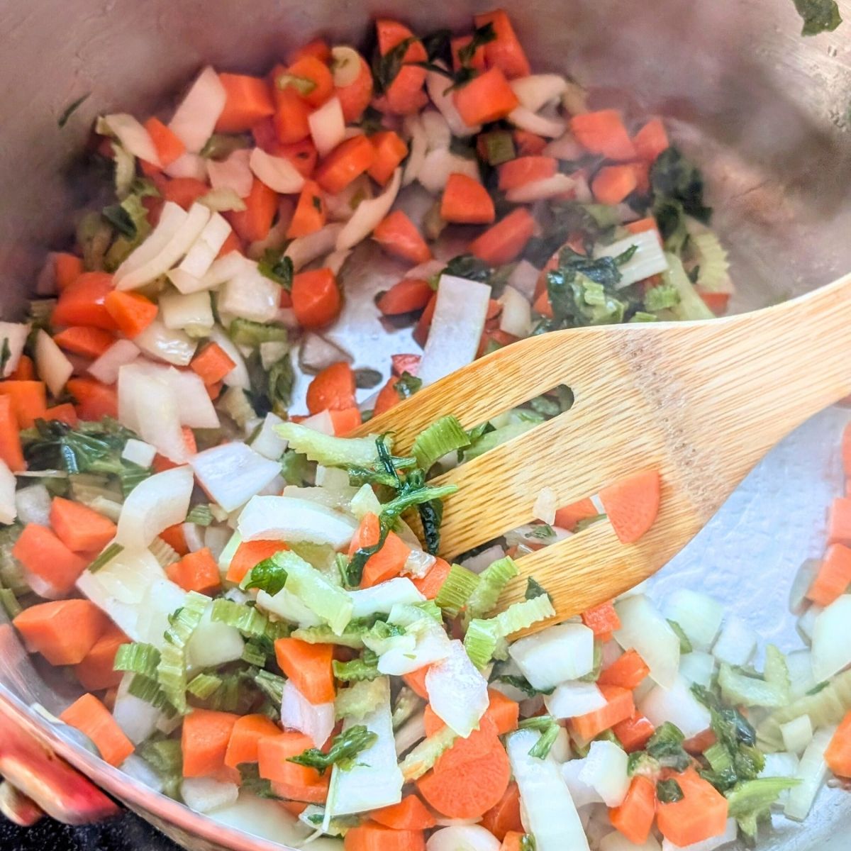 sauteed carrots, garlic, onions, and celery in a pot ready to make soup