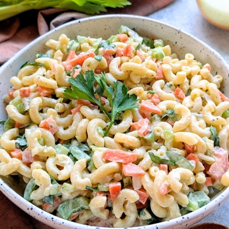 creamy ranch pasta salad with macaroni noodles in a bowl with celery chopped carrots and cherry tomatoes with a spoon.