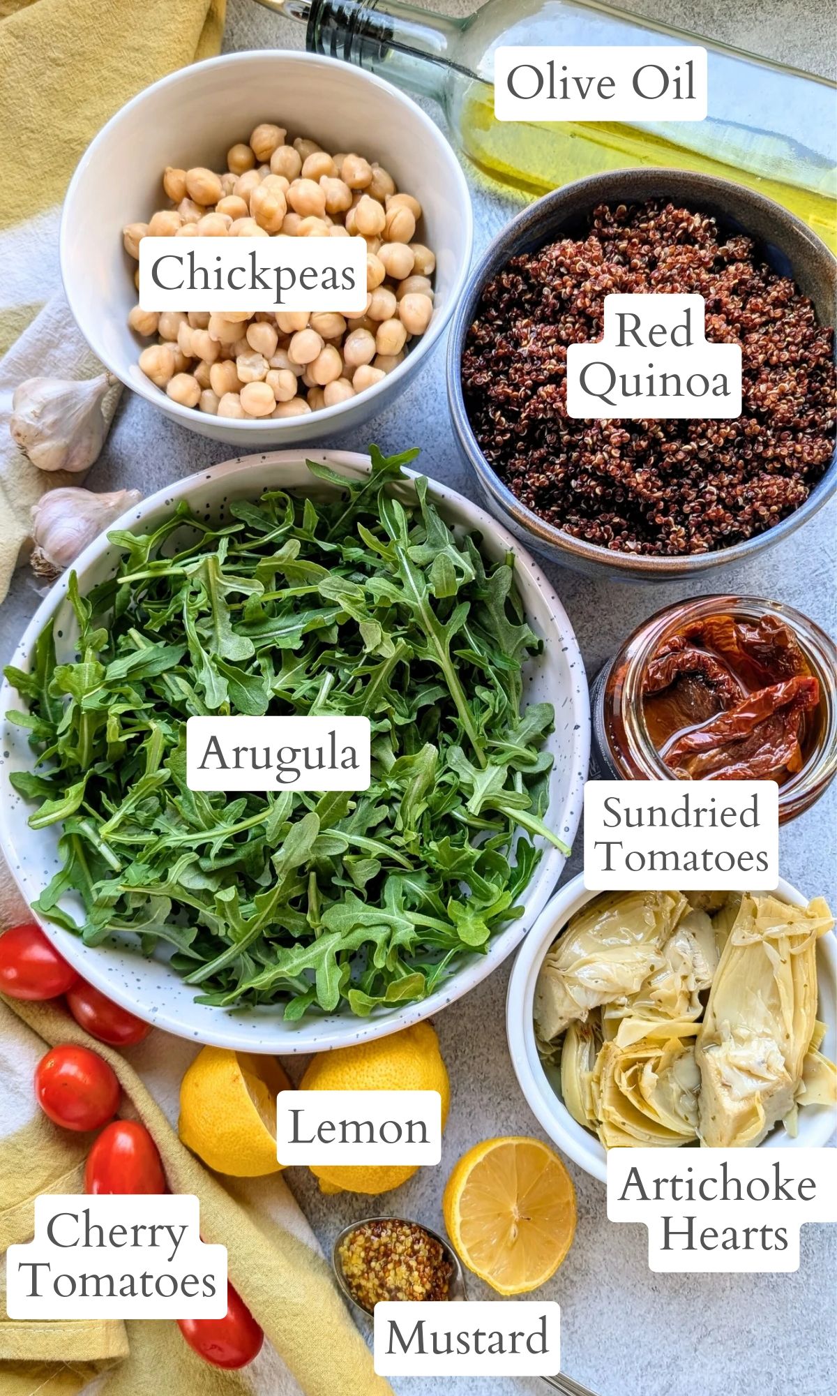 ingredients for arugula salad with quinoa, artichoke hearts, sun-dried tomatoes, lemon, chickpeas, and olive oil.