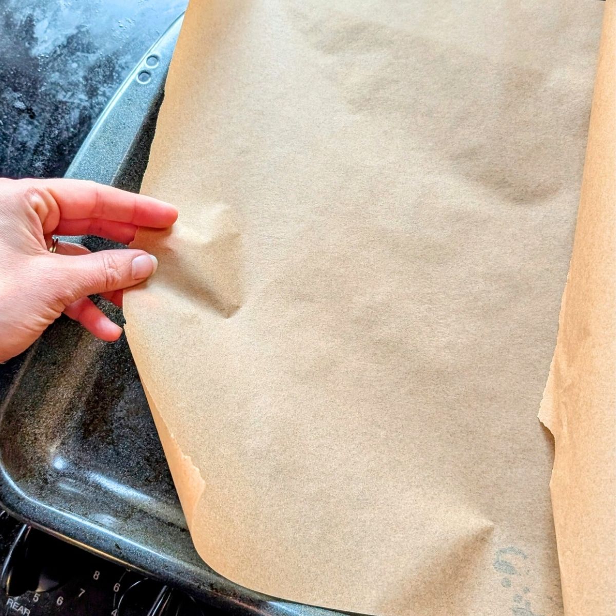 parchment paper being placed over a baking sheet pan