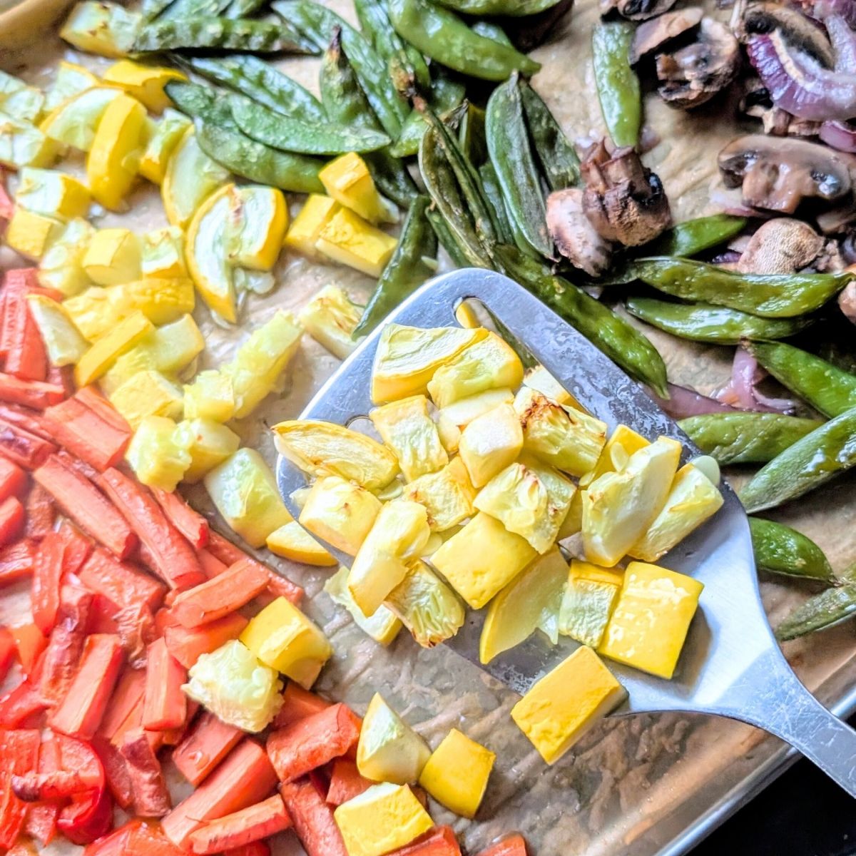 a spatula flipping sheet pan vegetables for stir fry