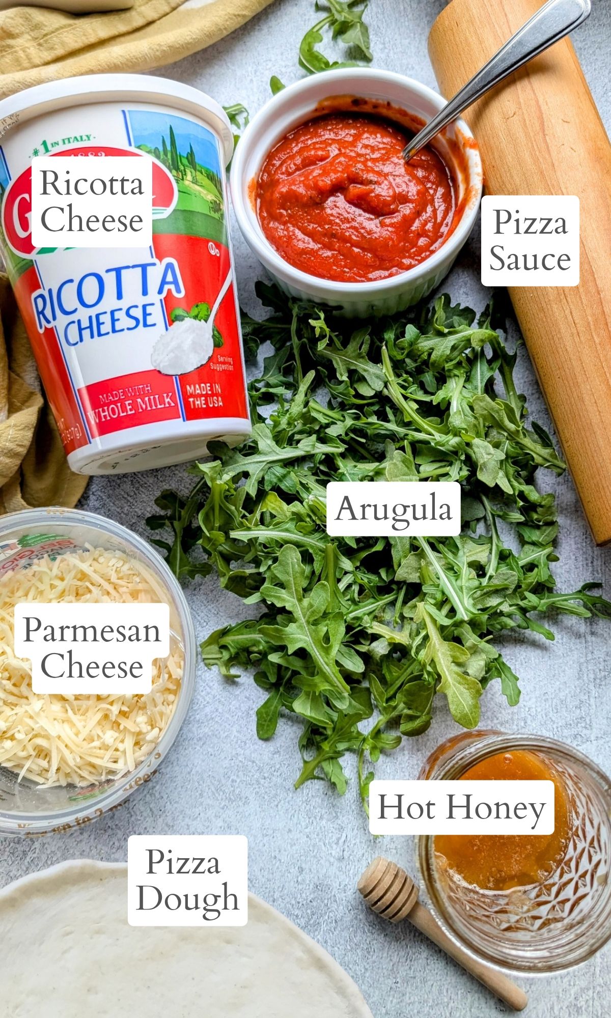 ingredients for ricotta arugula honey pizza with parmesan cheese and pizza sauce and crust