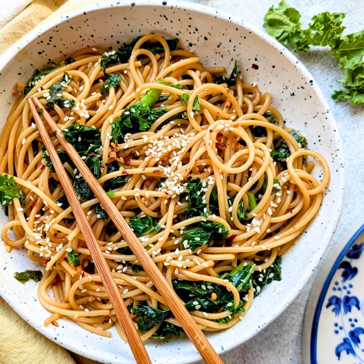 a bowl of spicy kale noodles with sesame seeds and fresh sauteed kale