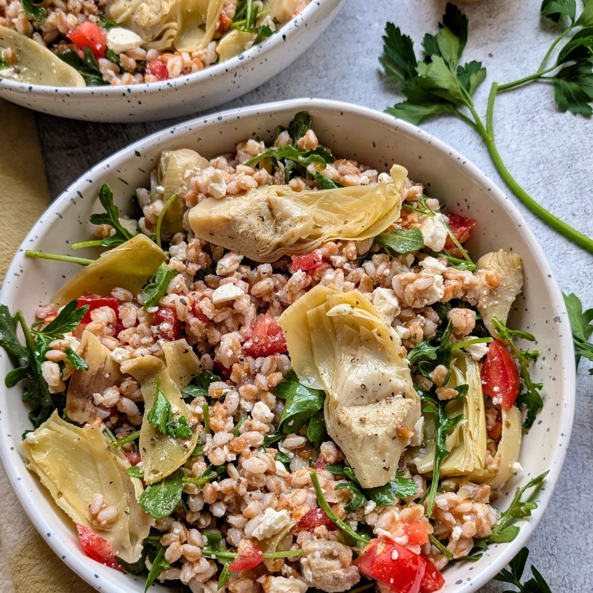 farro salad with artichoke hearts, arugula, and fresh tomatoes in a bowl for a hearty vegetarian lunch idea.