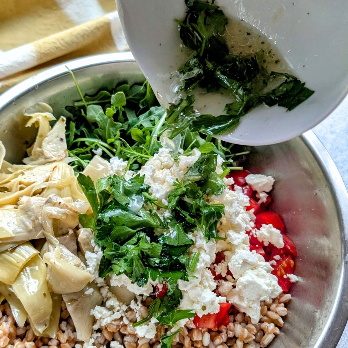 lemon vinaigrette dressing poured over farro salad with fresh vegetables.