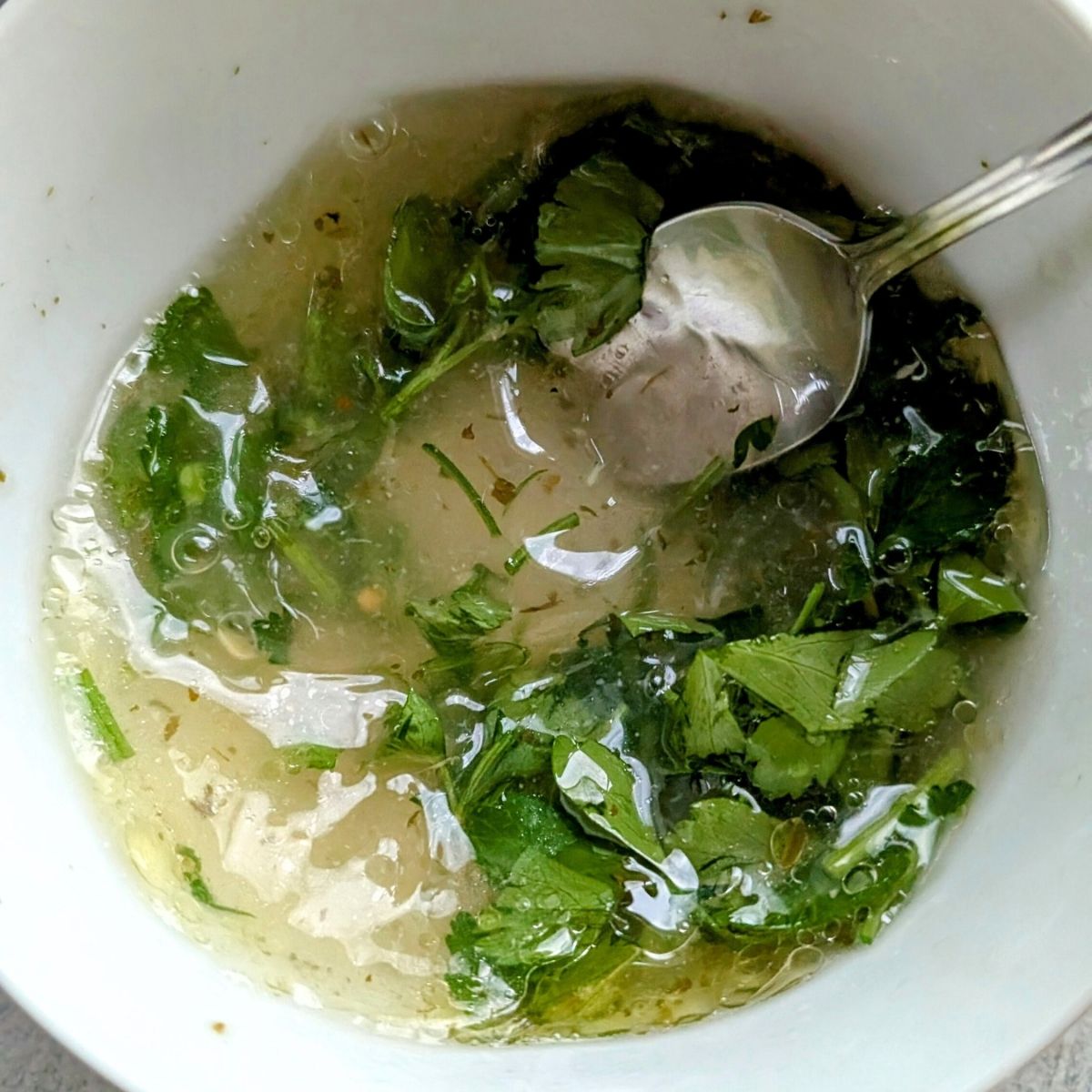 a small mixing bowl with olive oil, fresh lemon juice, and fresh parsley