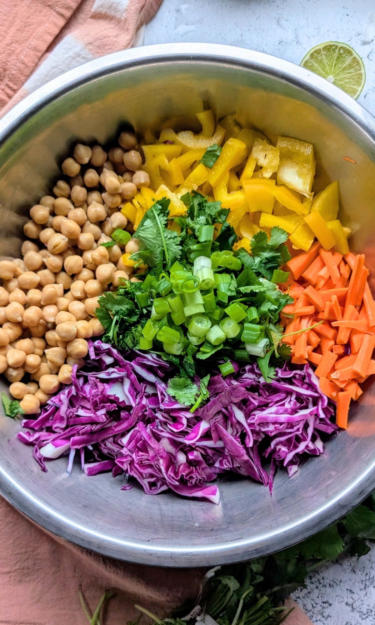 a large mixing bowl with chickpeas, peppers, carrots, cabbage, cilantro, and onions to make thai chickpea salad.