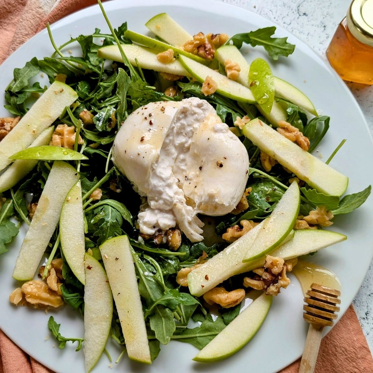 creamy honey burrata salad with apple and arugula with a sweet honey vinaigrette dressing.