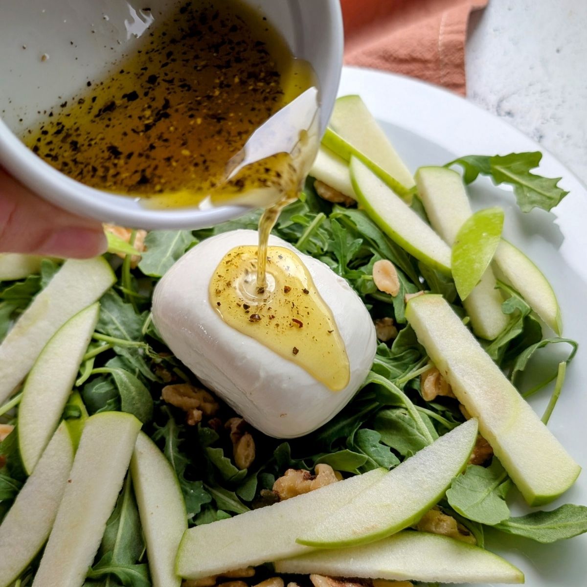 sweet and savory burrata salad with vinaigrette honey and apples with arugula and walnuts.