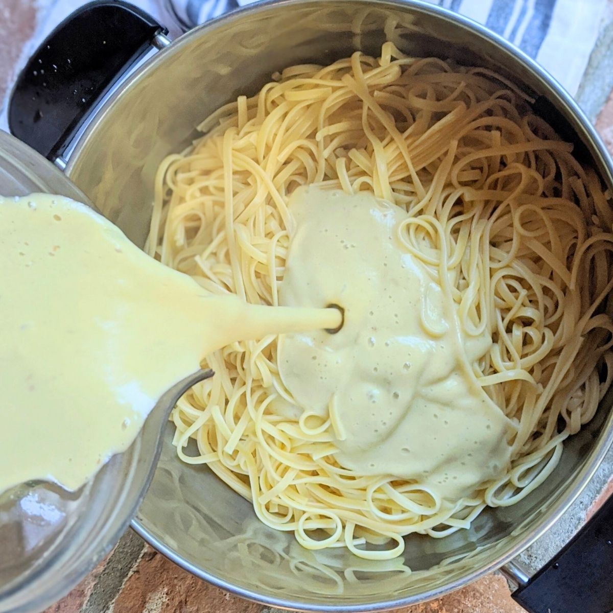 vegan alfredo sauce poured into cooked fettuccini noodles for a tasty homemade squash pasta.