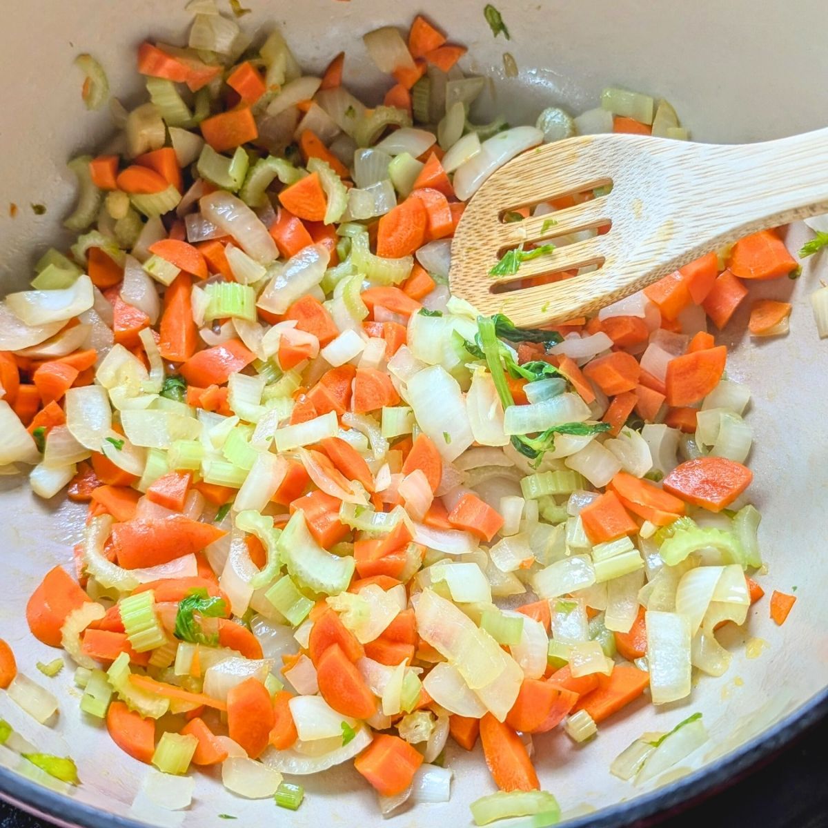 a pot with carrots, celery, onions, and garlic, to make corn chowder.