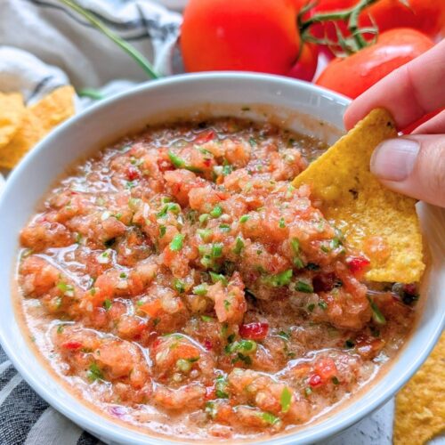 garlic scape pico de gallo salsa recipe with a hand dipping a tortilla chip into it