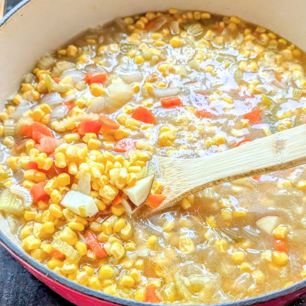 a pot of vegetables like corn and potatoes and carrots for breakfast.