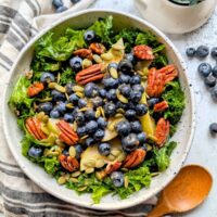 kale and pear salad with blueberries and nuts in a bowl with homemade dressing