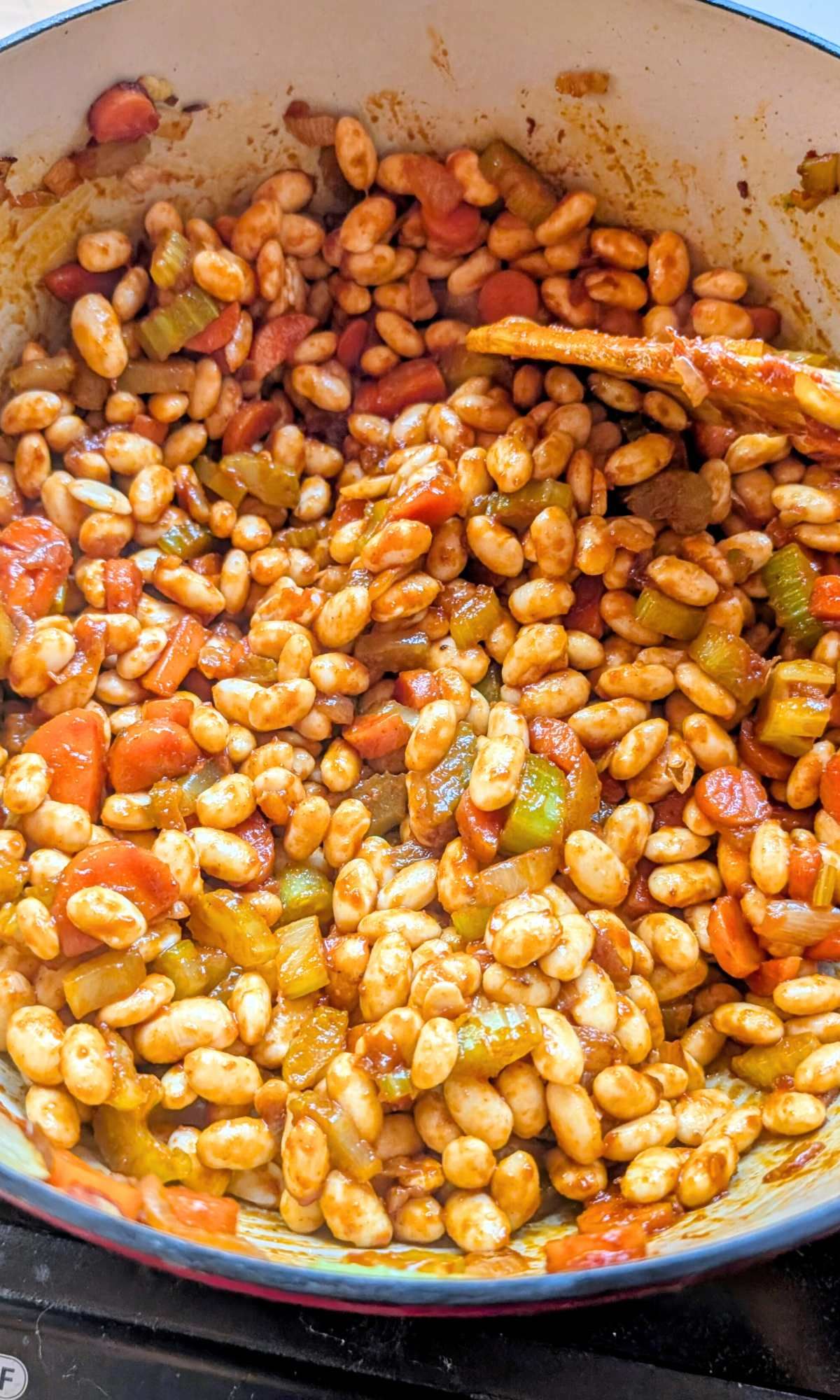 dried beans and tomatoes and spices added to a soup pot for greek fasolatha soup