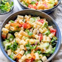 a big bowl of vegan pasta salad with ditalini noodles cucumber spinach tomatoes and olives in a red wine dressing for pasta salad.