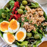 jammy egg salad with whole grain farro olives and roasted red peppers over mixed green lettuce